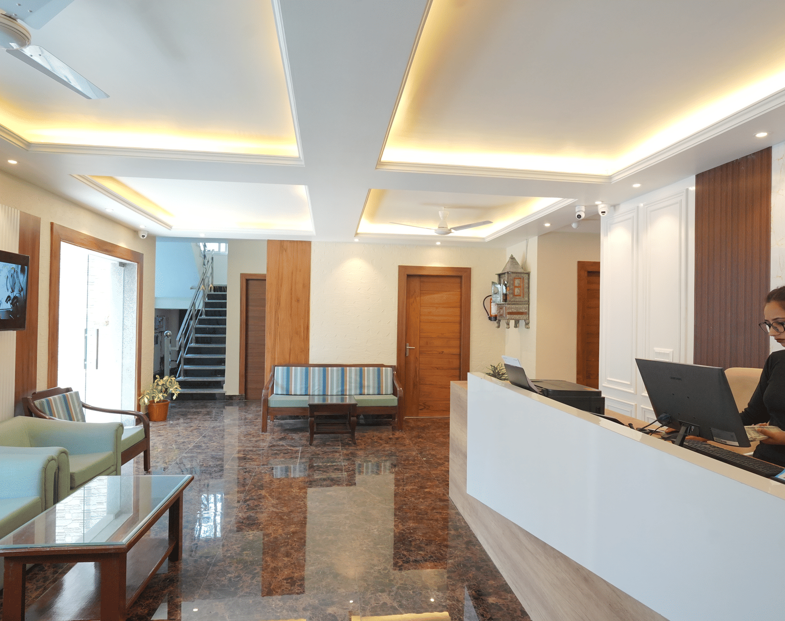 Reception area with a receptionist standing near the desk at DLS Oak Bush, Mussoorie.