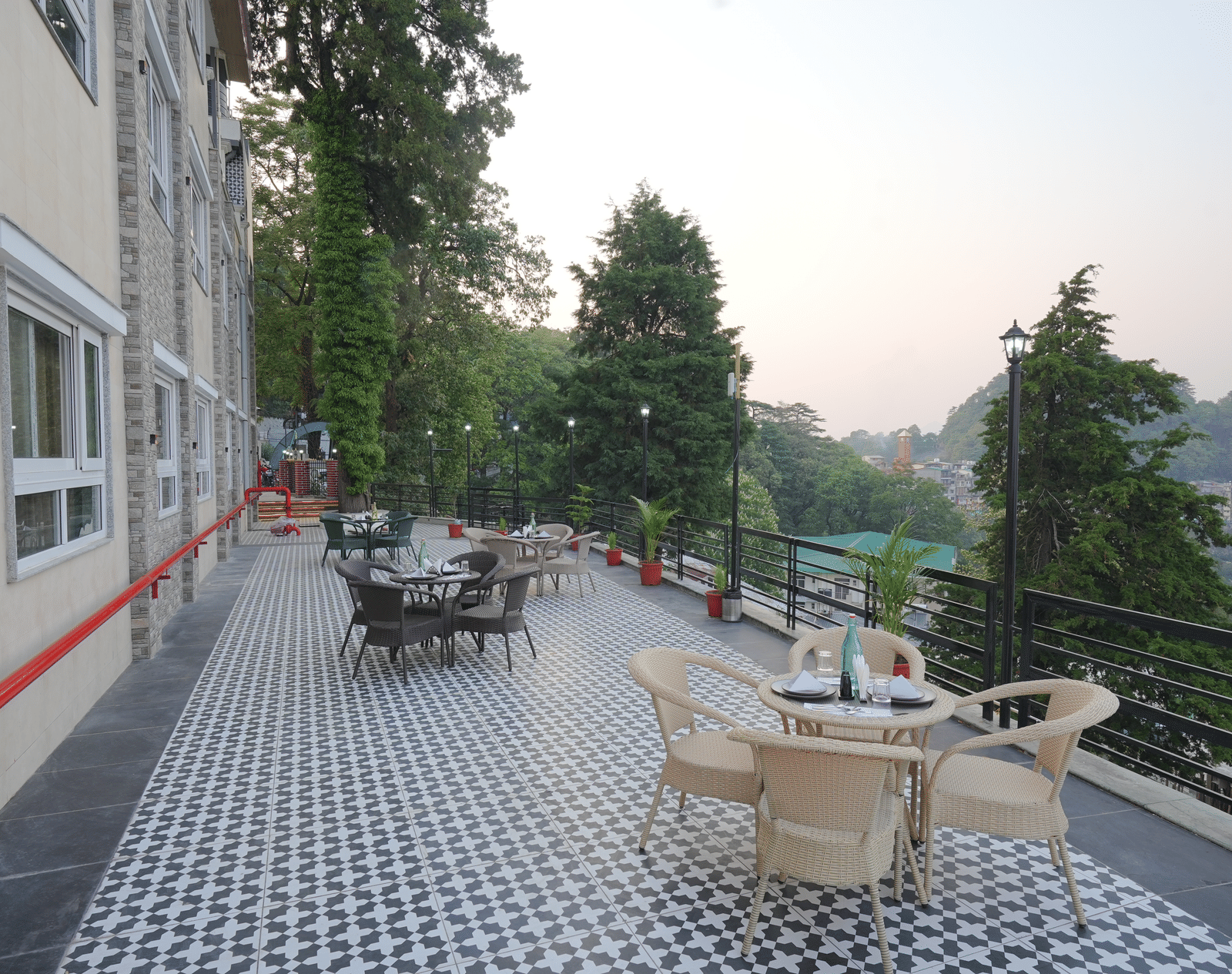 An outside seating area with comfortable chairs around tables at DLS Oak Bush, Mussoorie.