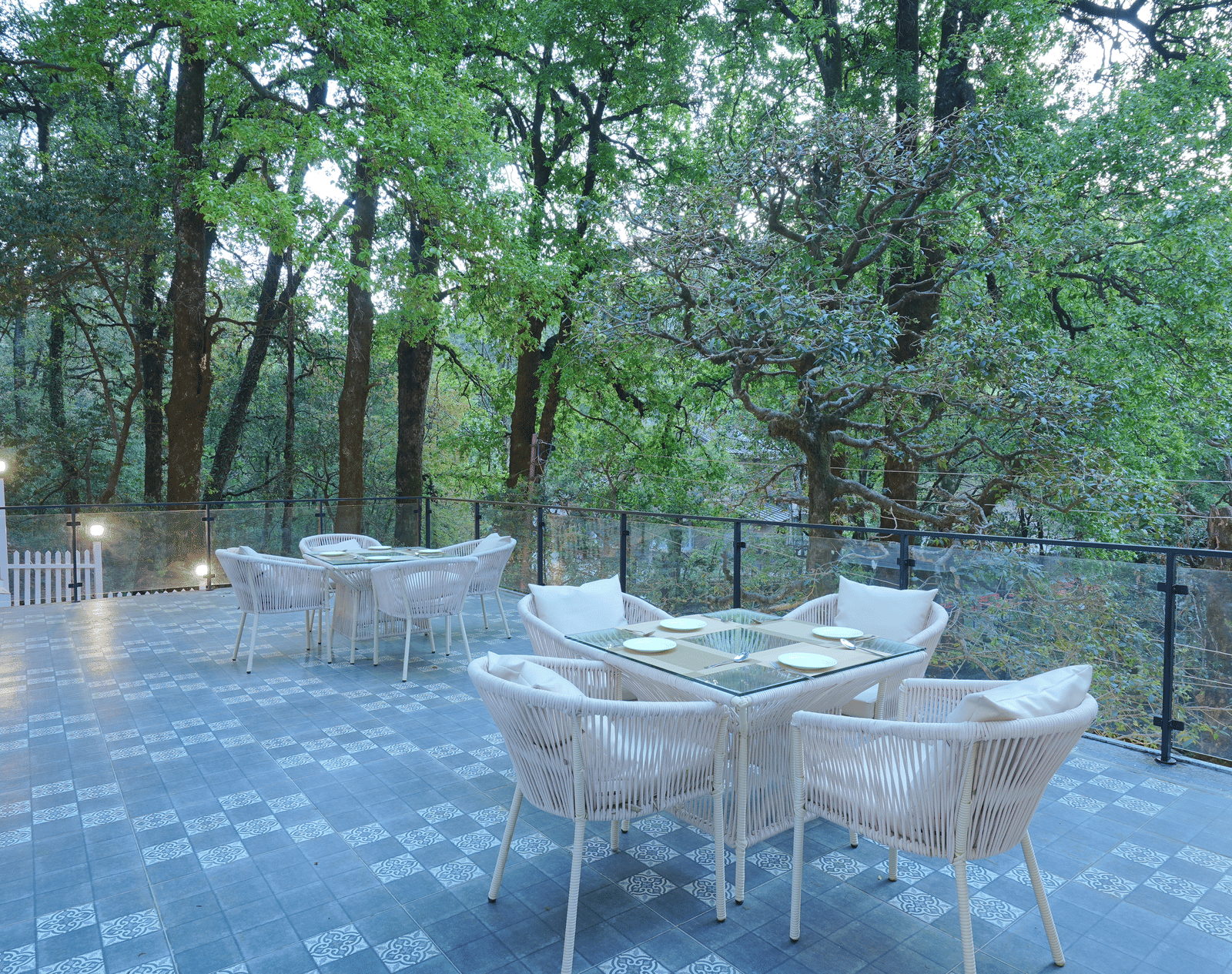 The deck at DLS The Emerald, Nainital featuring chairs and tables surrounded by trees