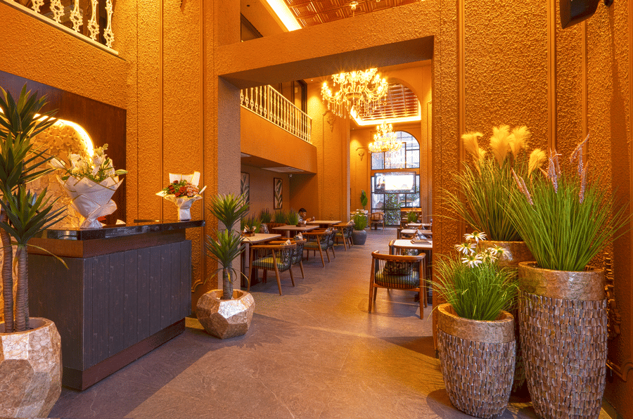 Exterior view of Cocobrisa showcasing the illuminated restaurant signage, elegant arched windows, landscaped entrance, staircase, and a welcoming modern façade at dusk.