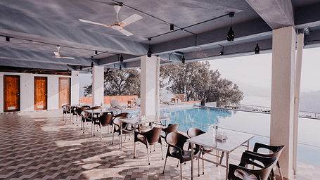 An image of the Pool Side Restaurant at Nisarga Lake Resort with the backdrop of the infinity pool and the lake
