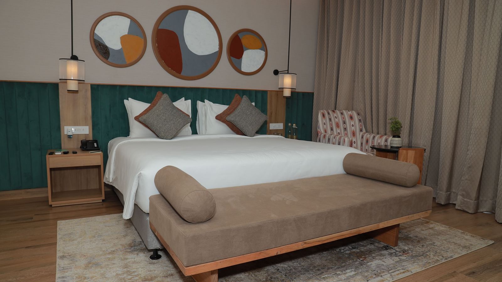 A bed with a bench and a beautiful wall painting above the headboard in our suite at Regency Tuticorin - Thoothukudi Hotel Rooms