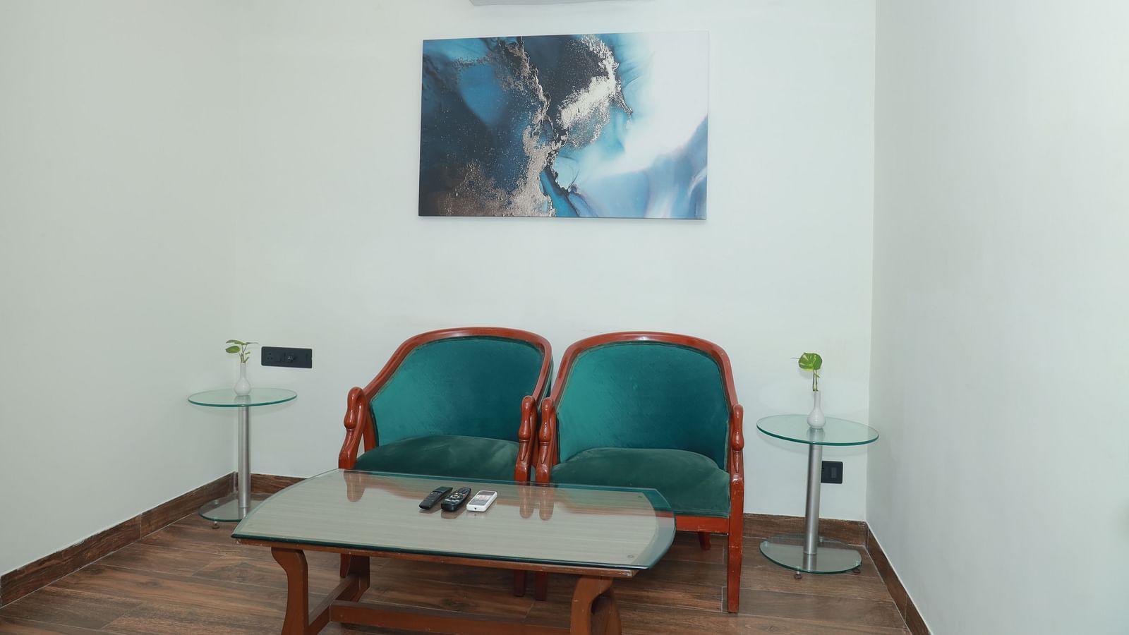 An image of two chairs in front of a table, with a beautiful painting on the wall behind them - Regency Tuticorin by GRT Hotels