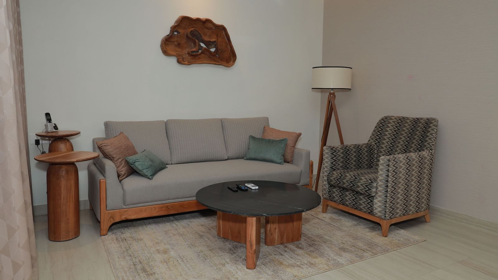 A relaxing area in our suite featuring a large couch with plush pillows, an upholstered chair, a coffee table, and a lamp to enhance the ambience - Regency Tuticorin by GRT Hotels