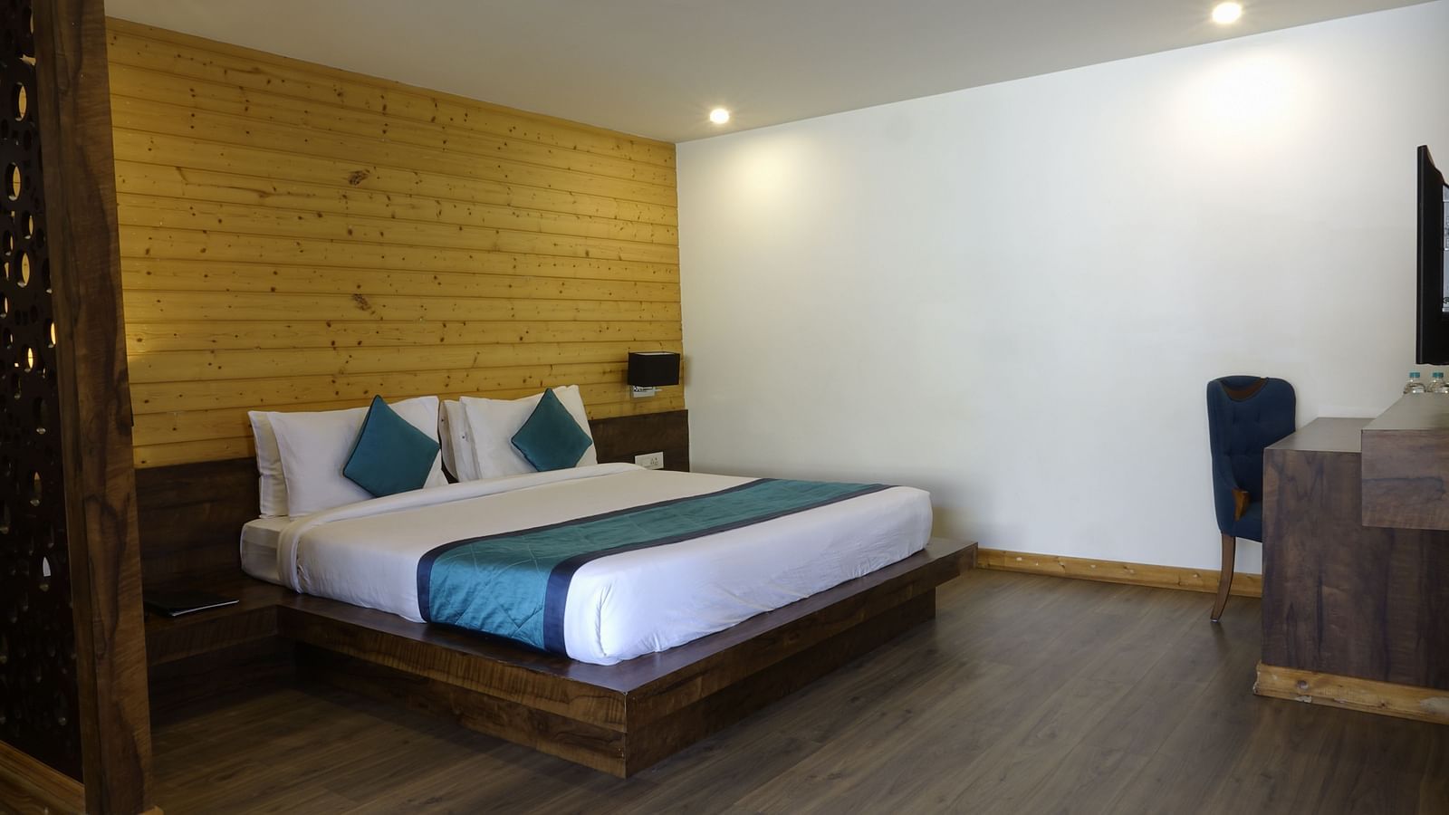 An image of an executive premium room with a bed, work desk, chair, and a wooden panelled accent wall behind the bed - Yashshree Sanderling, Darjeeling