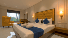 A double bed with a single seater high chair in view inside Deluxe Suite - Magnus Nexstar Suites, Pune