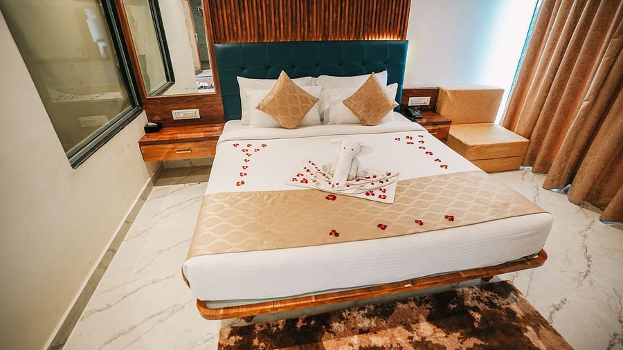 An image of a suite room featuring a bed with plush bedding, and bed side tables - Nisarga Lake Resort