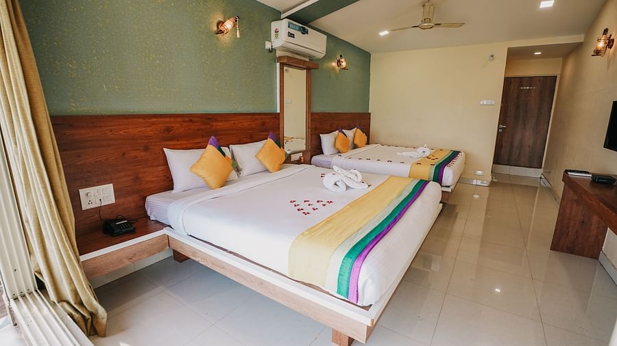 An image of a featuring two king size beds, bed side tables, a flat screen TV, and other room amenities - Nisarga Lake Resort