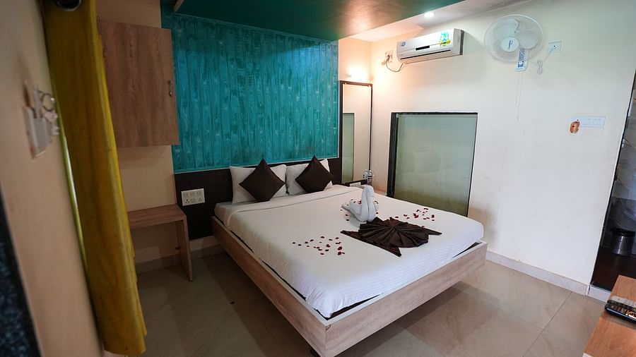 An image of a room with a bed, bed side tables, and air conditioner - Nisarga Lake Resort