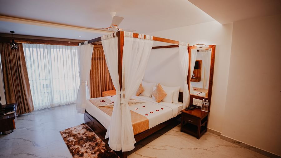 An  image of the presidential suite featuring a bed, bed side tables, a rug, and an expansive glass door leading to the balcony