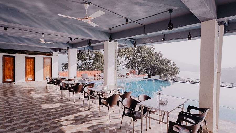 An image of the Pool Side Restaurant at Nisarga Lake Resort with the backdrop of the infinity pool and the lake