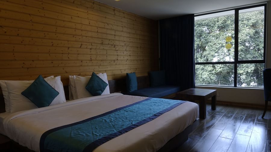 An image of a deluxe suite with a bed, a couch, a table, and an expansive window overlooking the view - Yashshree Sanderling, Darjeeling