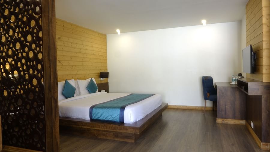 An image of an executive premium room with a bed, work desk, chair, flat scree TV, and a wooden panelled accent wall behind the bed - Yashshree Sanderling, Darjeeling