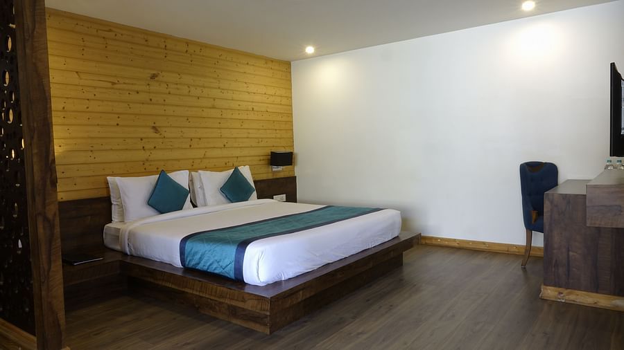 An image of an executive premium room with a bed, work desk, chair, and a wooden panelled accent wall behind the bed - Yashshree Sanderling, Darjeeling