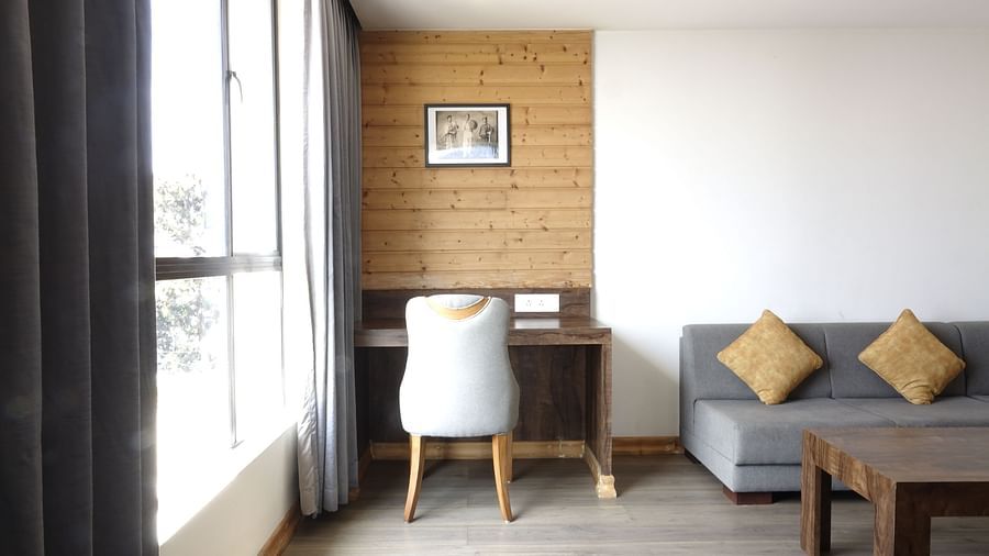 An image of a premium suite with a couch, a table, a work desk, a chair, and an expansive window - Yashshree Sanderling, Darjeeling