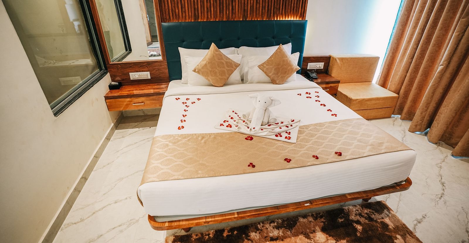 An image of a suite room featuring a bed with plush bedding, and bed side tables - Nisarga Lake Resort