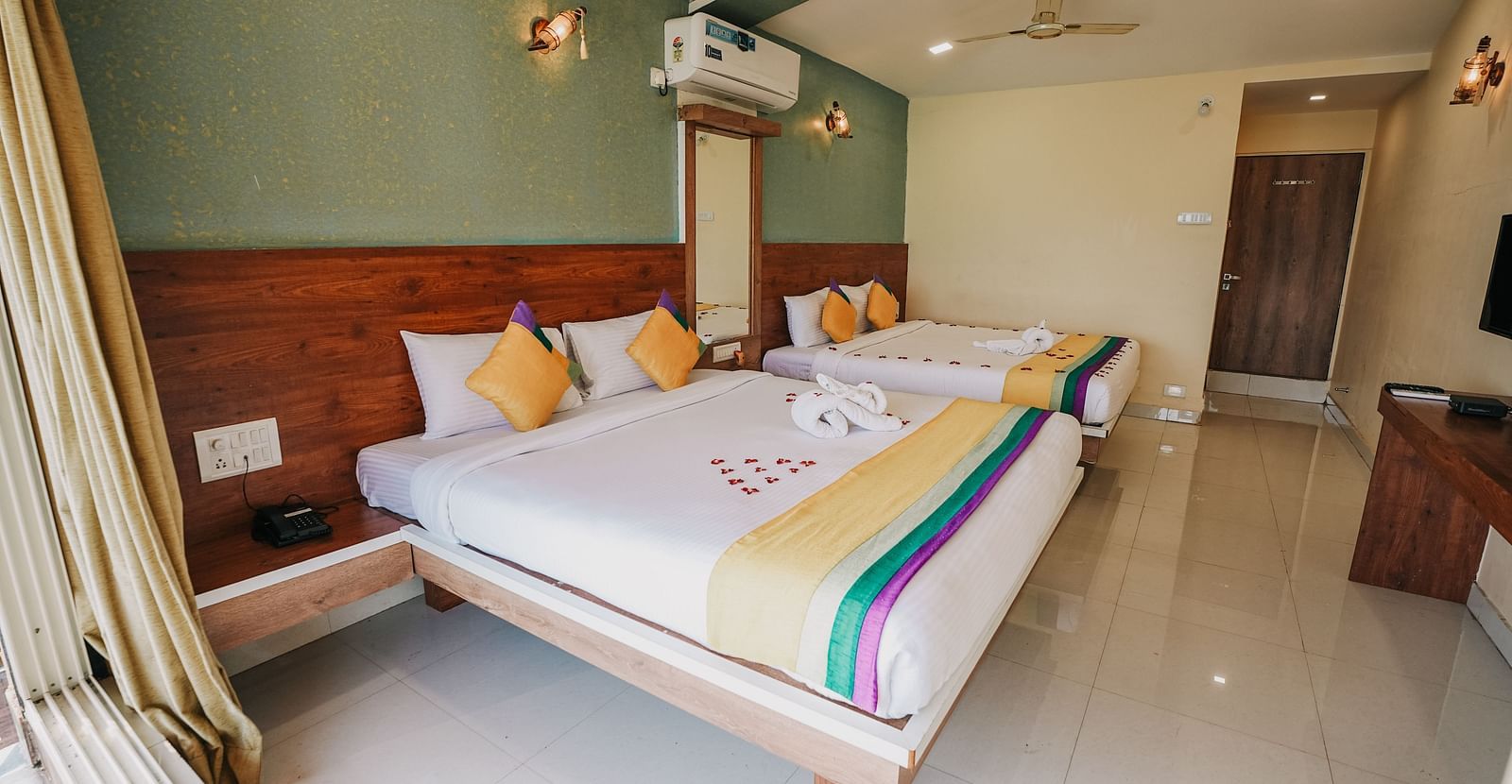 An image of a featuring two king size beds, bed side tables, a flat screen TV, and other room amenities - Nisarga Lake Resort