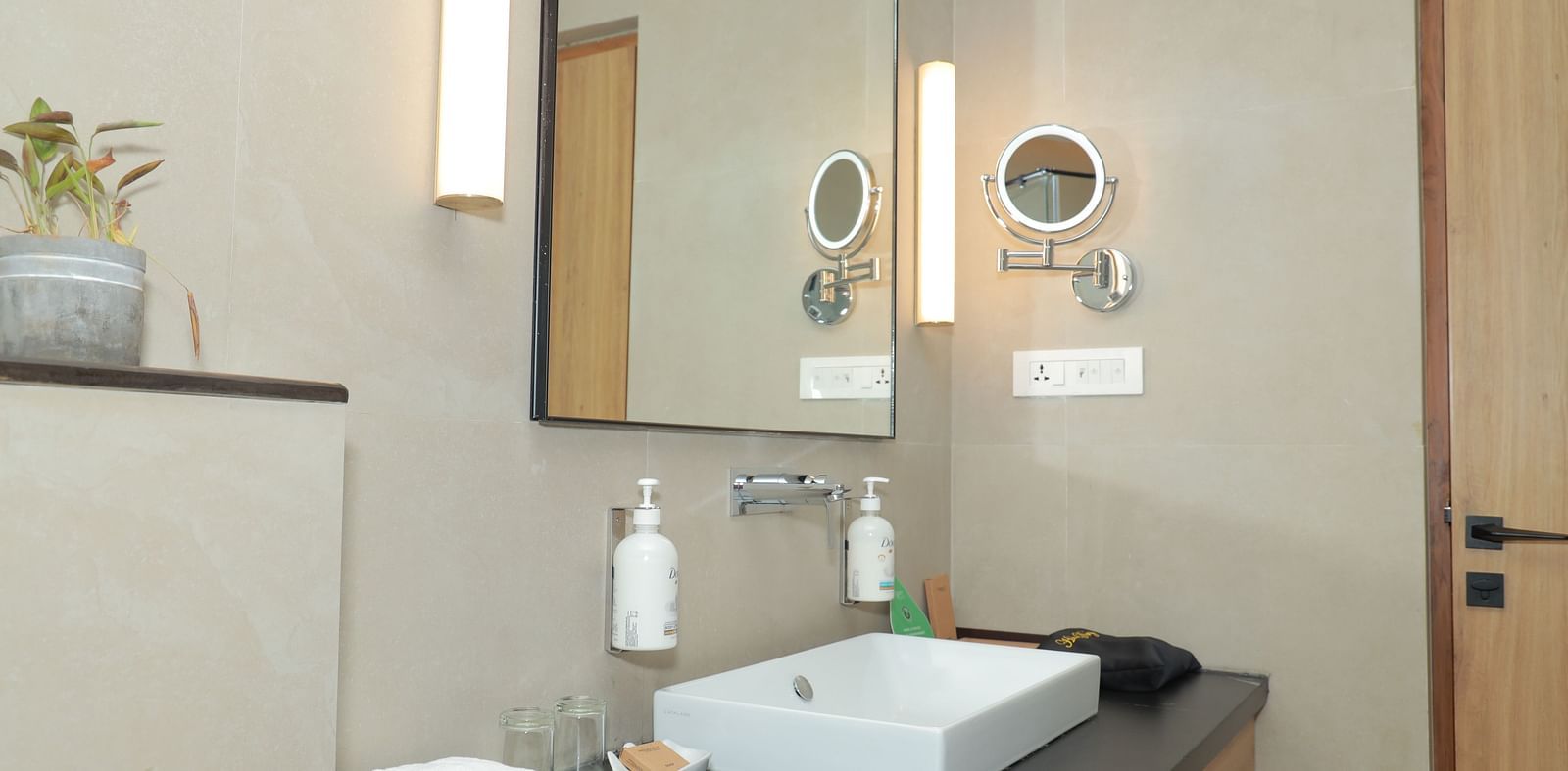 An image of the vanity counter in our washroom, with toiletries placed near the sink and a self-magnifying mirror on the wall - Regency Tuticorin by GRT Hotels