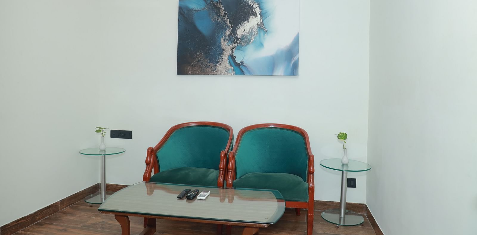 An image of two chairs in front of a table, with a beautiful painting on the wall behind them - Regency Tuticorin by GRT Hotels