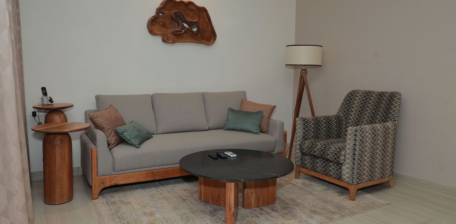 A relaxing area in our suite featuring a large couch with plush pillows, an upholstered chair, a coffee table, and a lamp to enhance the ambience - Regency Tuticorin by GRT Hotels