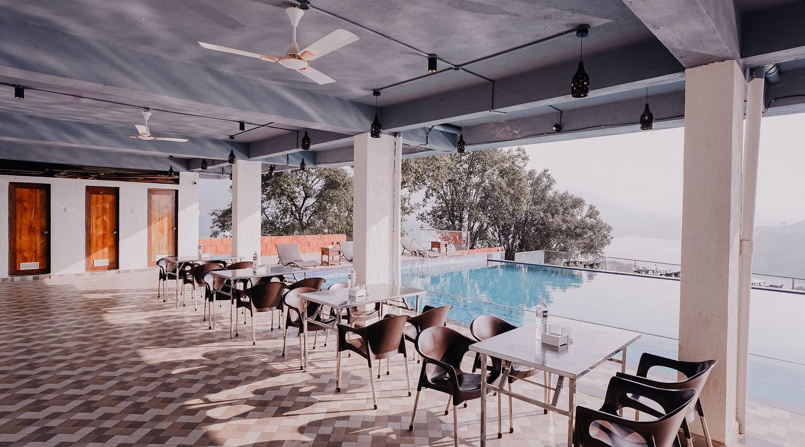 An image of the Pool Side Restaurant at Nisarga Lake Resort with the backdrop of the infinity pool and the lake