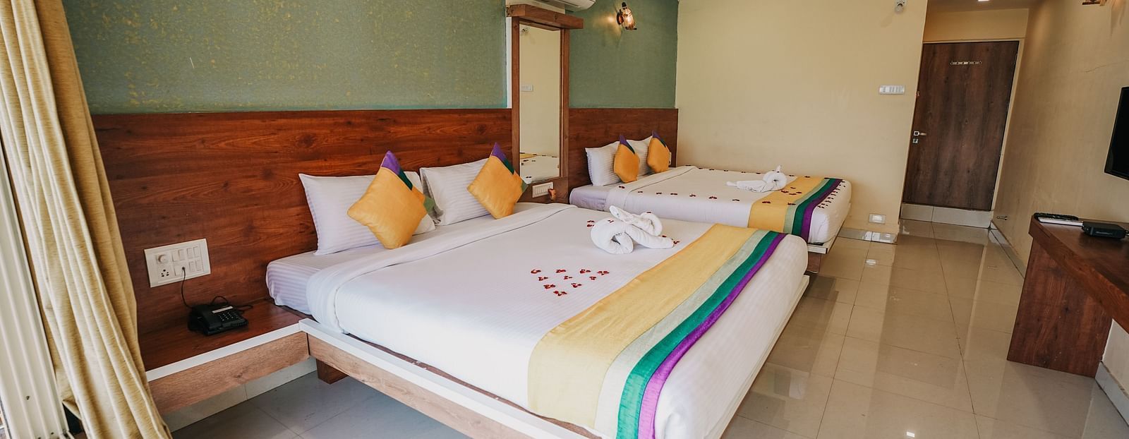 An image of a featuring two king size beds, bed side tables, a flat screen TV, and other room amenities - Nisarga Lake Resort