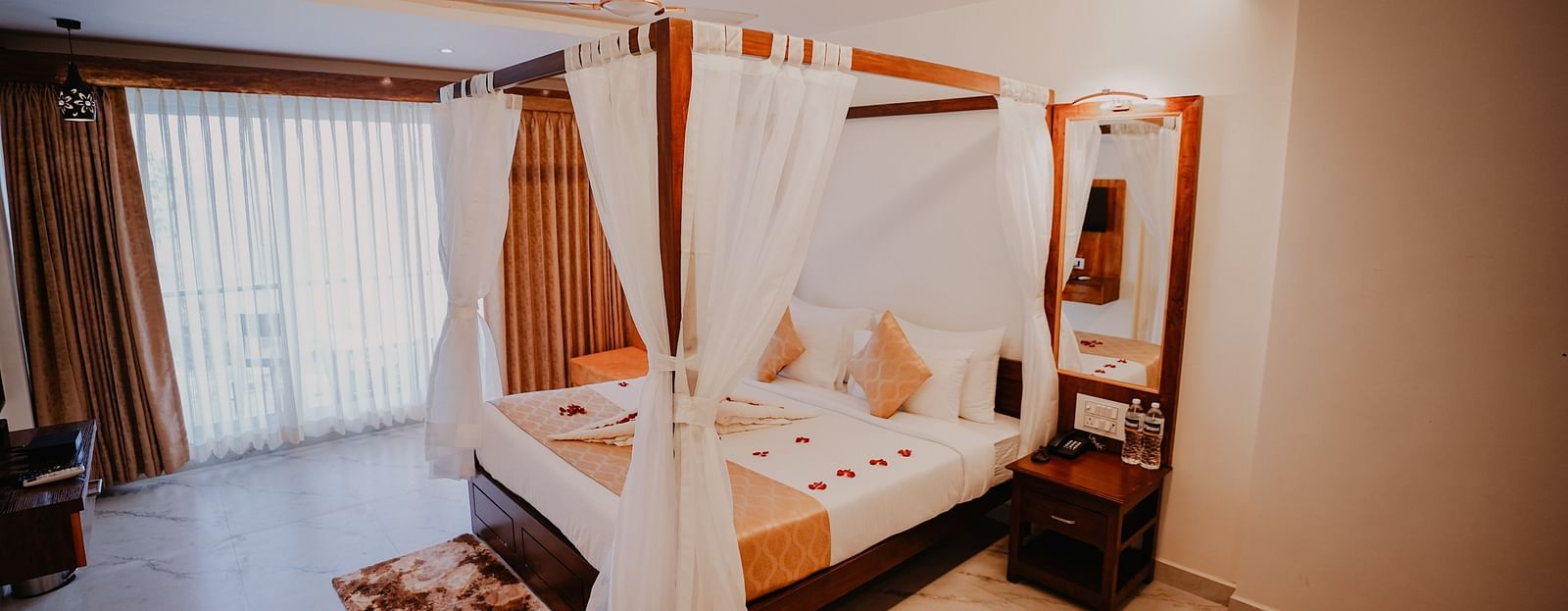 An  image of the presidential suite featuring a bed, bed side tables, a rug, and an expansive glass door leading to the balcony