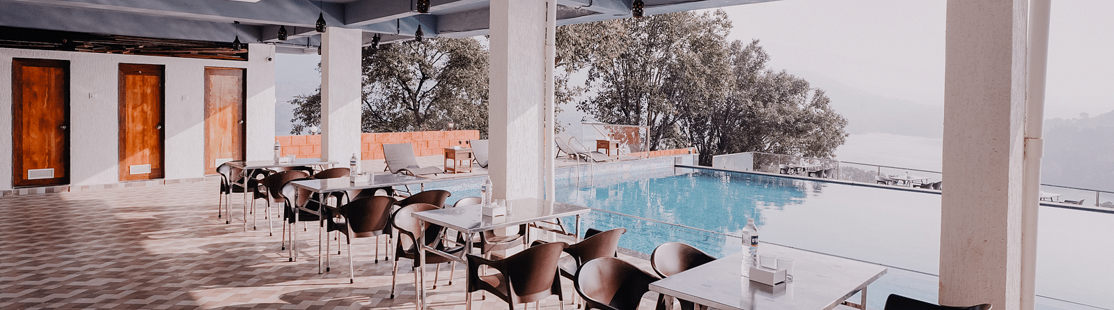 An image of the Pool Side Restaurant at Nisarga Lake Resort with the backdrop of the infinity pool and the lake