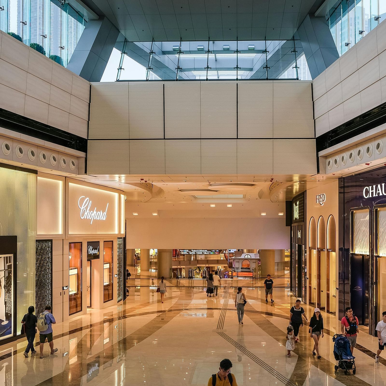 Storefronts of luxury boutiques including Chaumet, Louis Vuitton, and Chopard, displaying brand logos and window displays.