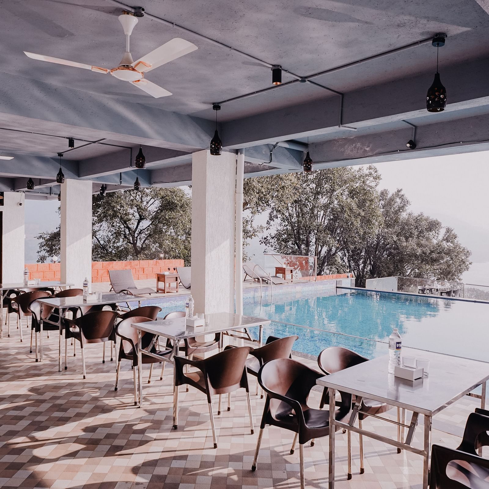 An image of the Pool Side Restaurant at Nisarga Lake Resort with the backdrop of the infinity pool and the lake
