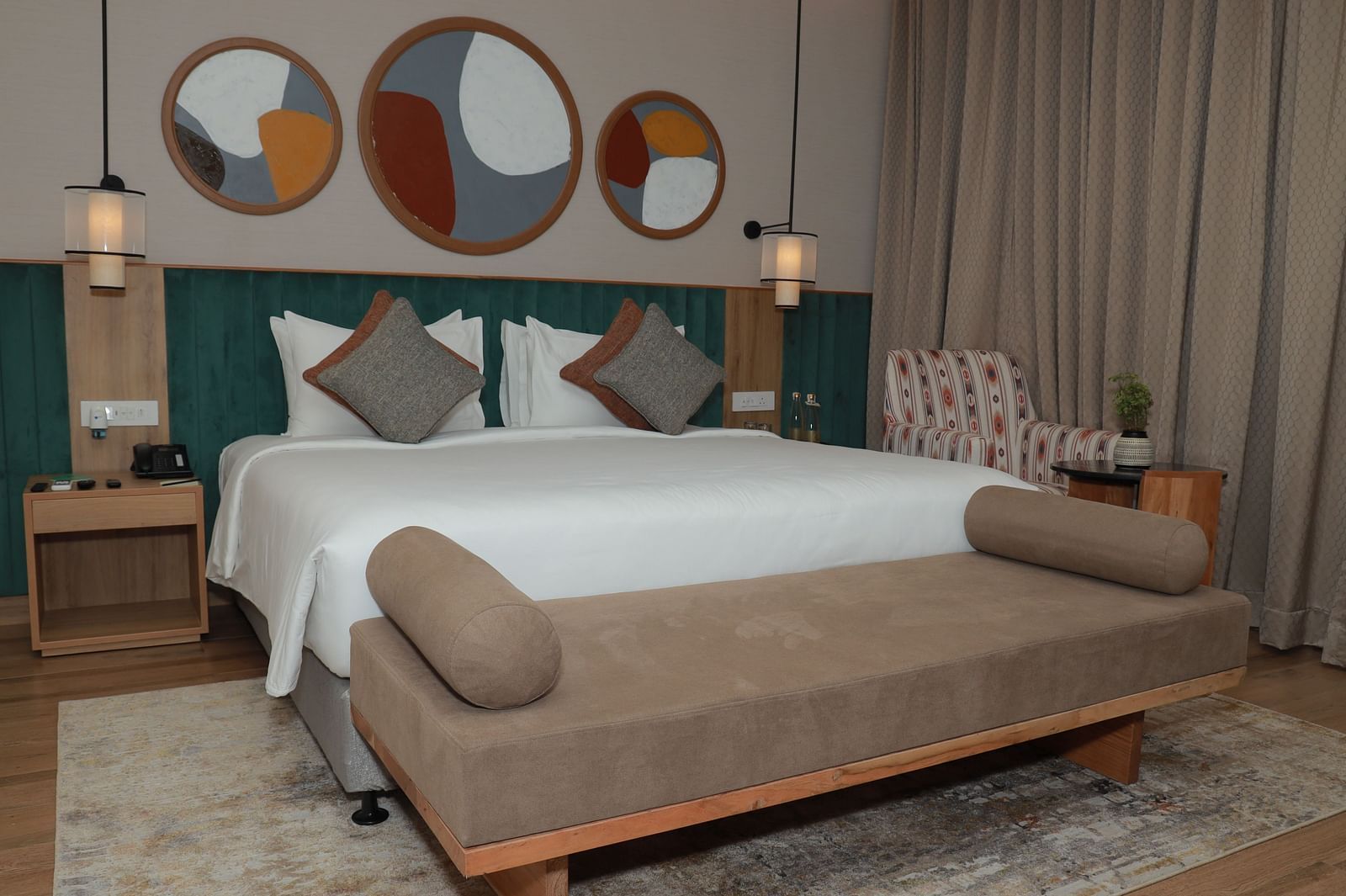 A bed with a bench and a beautiful wall painting above the headboard in our suite at Regency Tuticorin - Thoothukudi Hotel Rooms