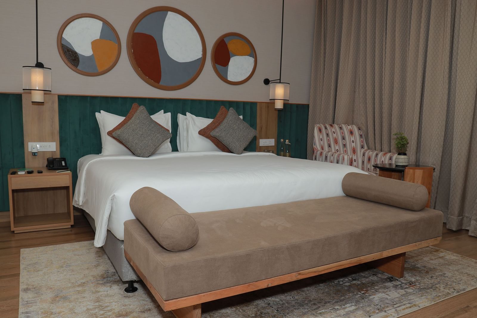 A bed with a bench and a beautiful wall painting above the headboard in our suite at Regency Tuticorin - Thoothukudi Hotel Rooms
