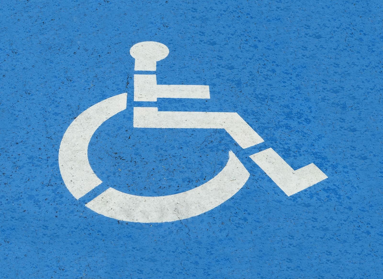 White wheelchair accessibility symbol on a blue background, indicating facilities for differently-abled individuals
