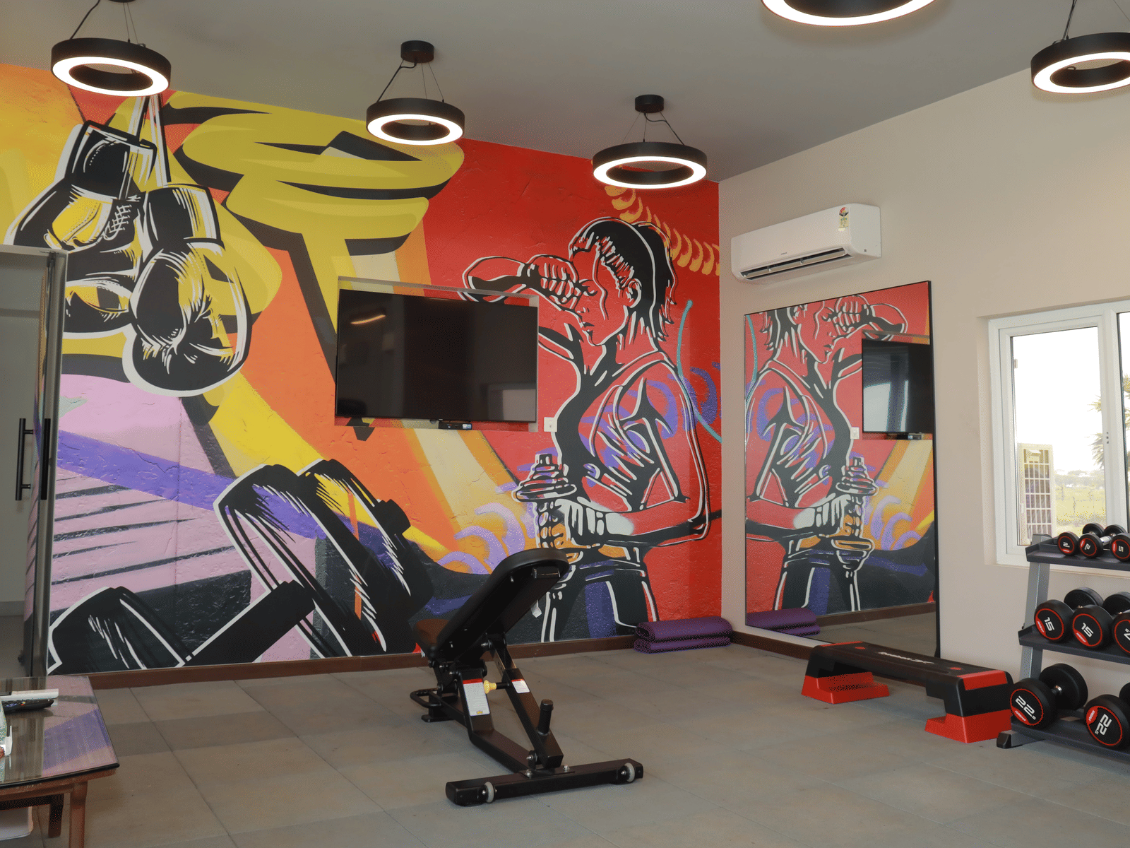 An image of our gym in Tuticorin with a wall mounted television, a locker and gym equipment like dumbbell rack and incline bench press - Regency Tuticorin by GRT Hotels, Best Hotel in Tuticorin