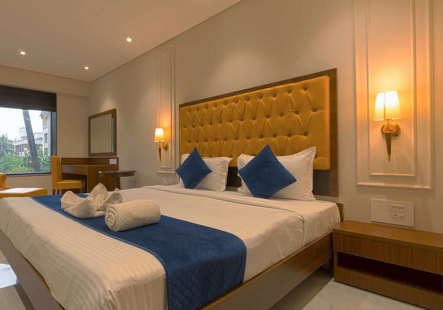 A double bed with a single seater high chair in view inside Deluxe Suite - Magnus Nexstar Suites, Pune