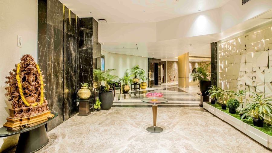 Elegant hotel entrance with a golden statue, plants, and a warmly lit interior | The Citi Residenci Hotel Durgapur
