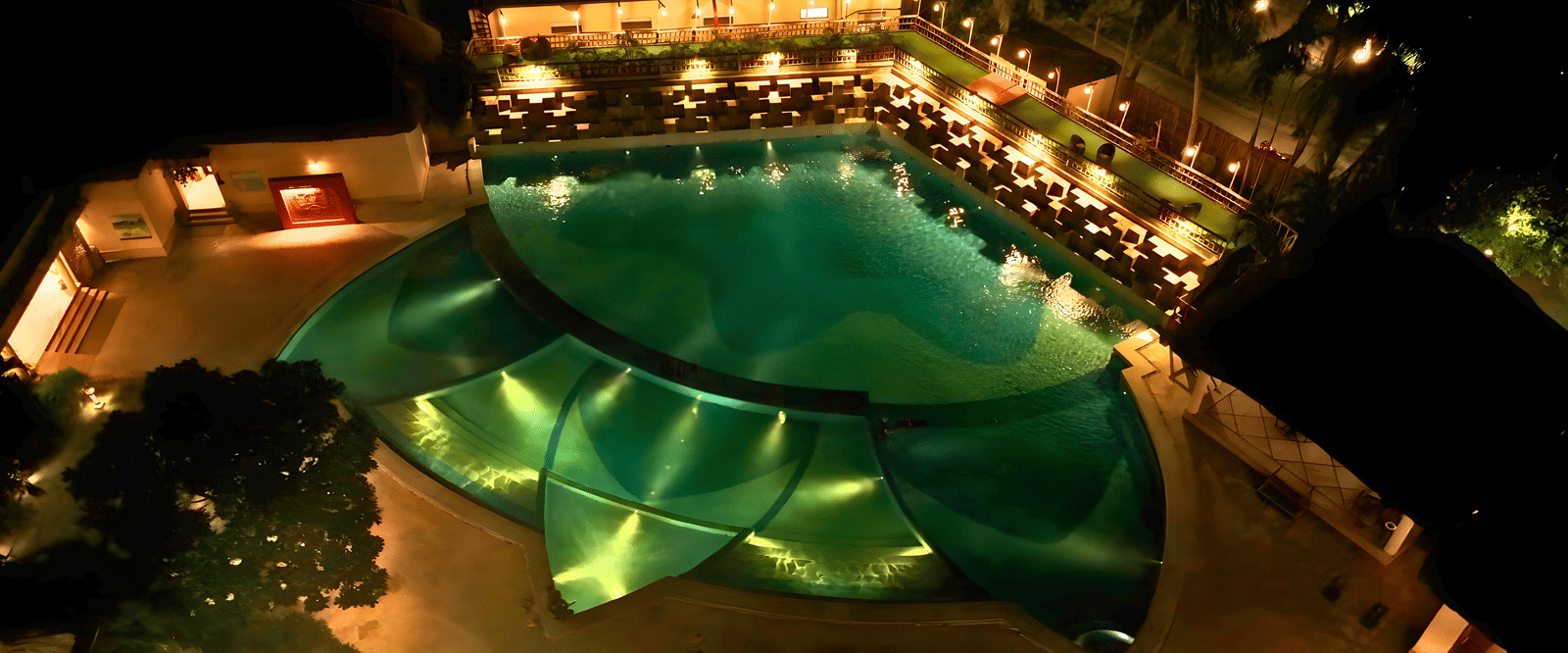 An aerial view shows a beautifully lit resort pool area at night | Vedic Village Spa Resort, Kolkata
