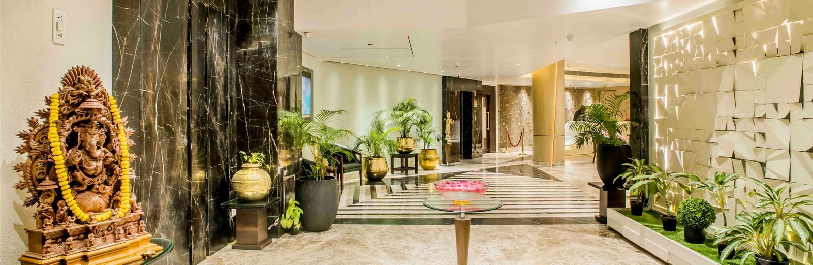 Elegant hotel entrance with a golden statue, plants, and a warmly lit interior | The Citi Residenci Hotel Durgapur