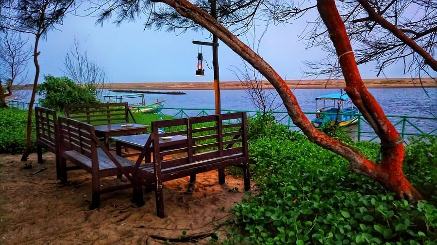 A seating area with a table in the centre, set beside a serene lake view at Lotus Eco Beach Resort Konark.
