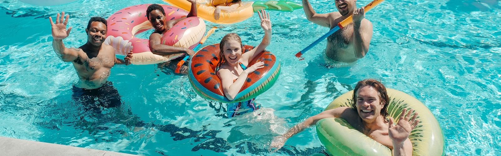 a group of people posing for the camera in a swimming pool during daytime