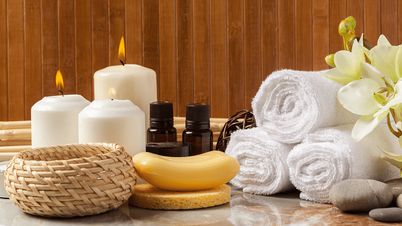 Image of towels beautifully wrapped and placed next to candles and two bottles of essential oils