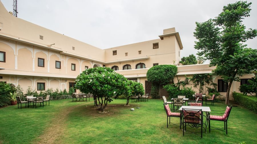 An outdoor seating area on a well-kept lawn with a building of Royal Heritage Haveli in the background.