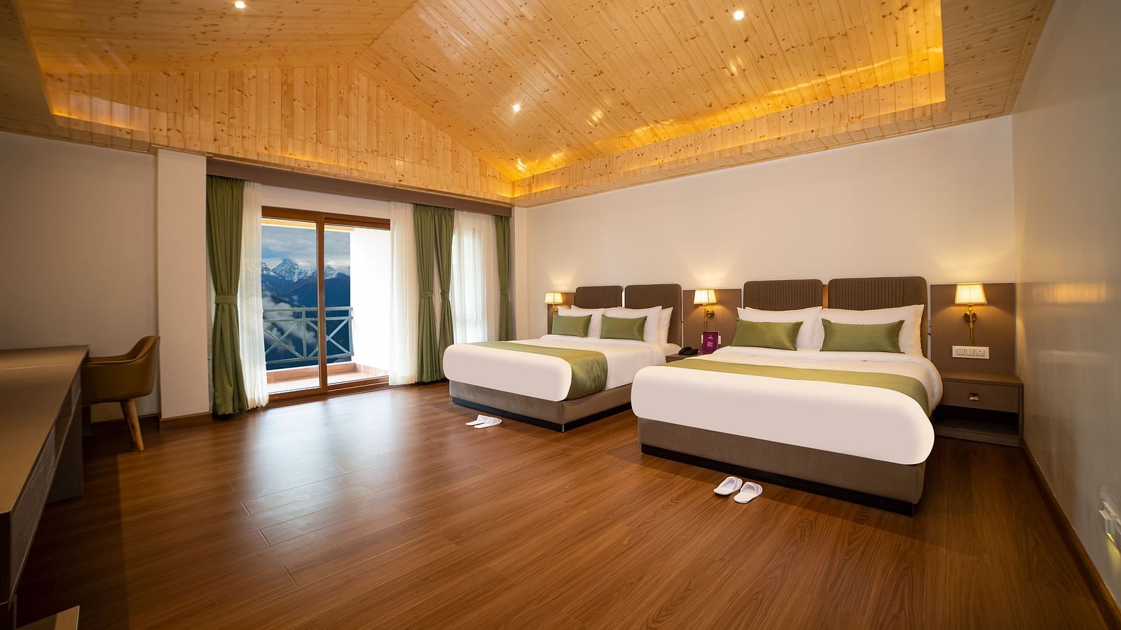Spacious hotel room with two large beds, wooden flooring, a desk and chair, warm ceiling lighting, and a balcony with a scenic view - Yashshree Pelling Chekhim Retreat.