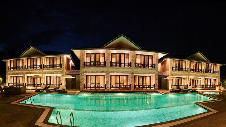 Night view of a hotel building reflected in a lit swimming pool - Royal Tulip, Chitwan