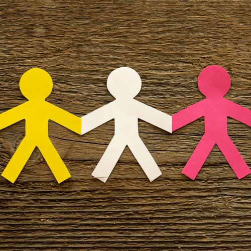 A row of colourful paper cut-out figures holding hands against a wooden background.