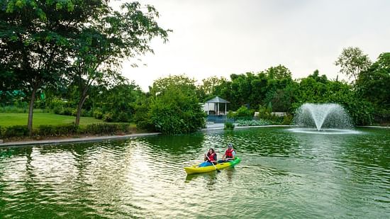 An image of a couple boating in a lake at Karma Lakelands amidst lush greenery