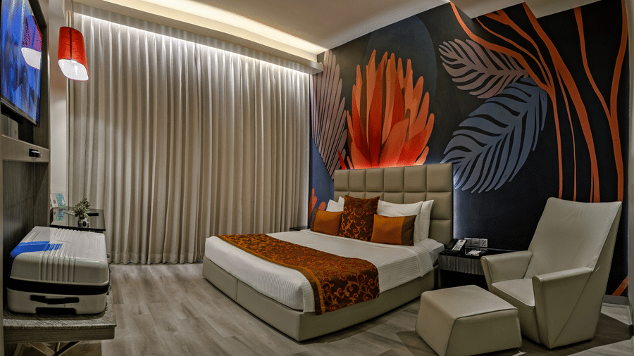 Suite bedroom at The Sonnet, Kolkata with a double bed, lounge chairs, bedside tables and a television.