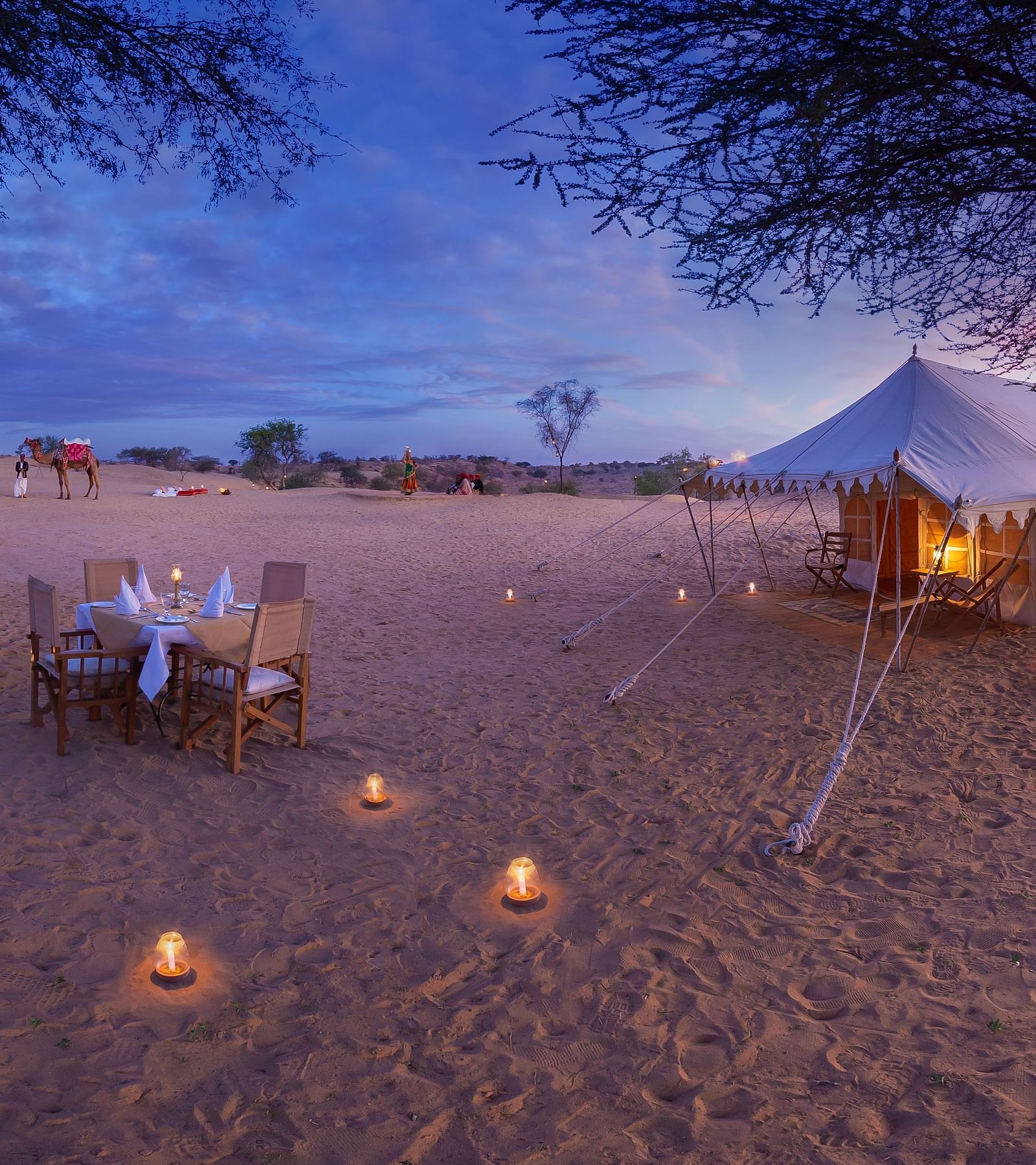 Manvar private camp  a hut and a outdoor table setting with lights all around - MANVAR Resort & Desert Camp