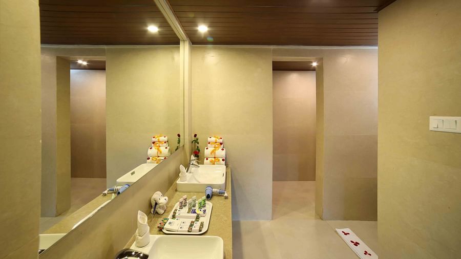 Bathroom of a suite at Uday Backwater Resort featuring a spacious sink area with a large mirror above and neatly arranged toiletries beside it