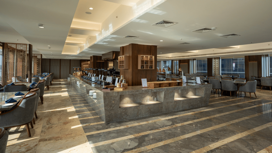 A spacious and modern buffet dining area with marble flooring and sleek food service counters - Praveg's Grand Eulogia, Ahmedabad